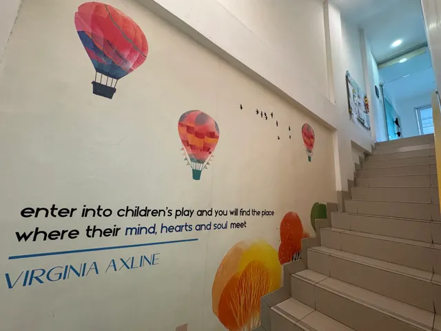 Stairway beside a wall decorated with hot-air balloons and a quotation about play