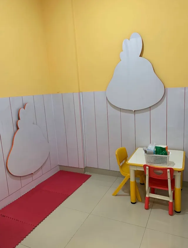 Small table with red and yellow chairs, rabbit-shaped wall decorations, and a red floor mat