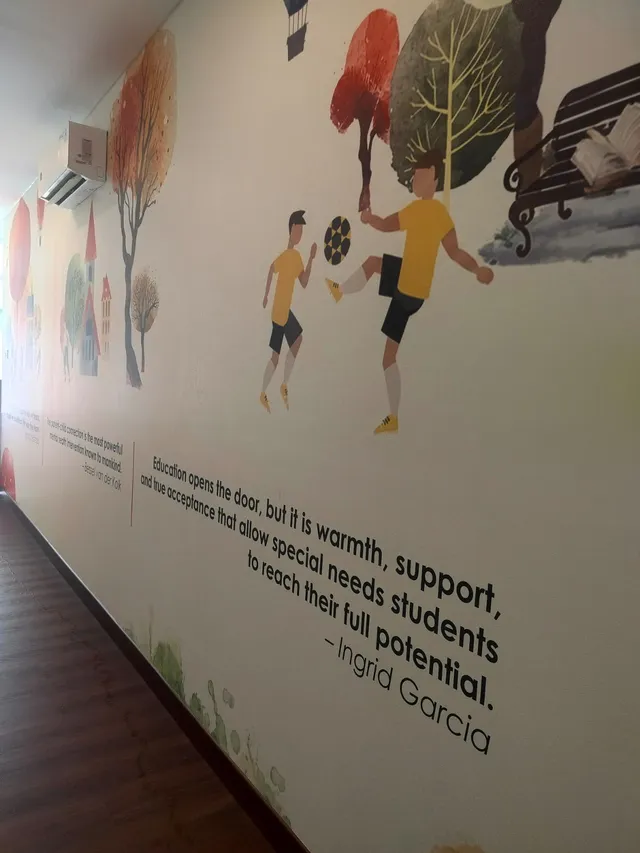 Hallway wall with illustrations of children playing ball, trees, and quotations about support and education