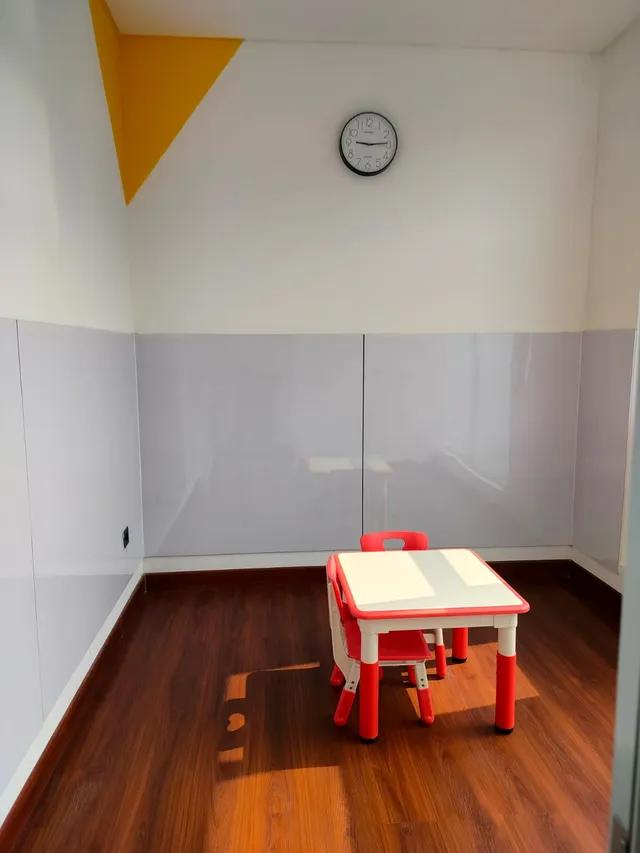 Room with a wooden floor and a small red table and chairs