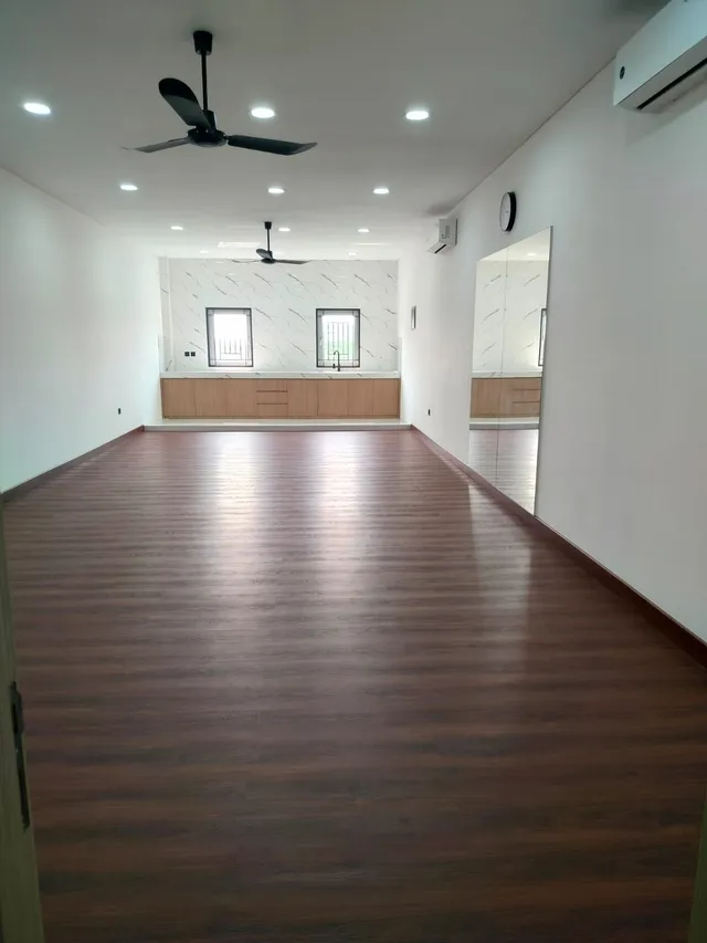 Open room with a wooden floor and windows at the far end
